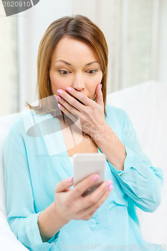 Image of surprised woman with smartphone at home