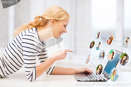 Image of smiling student girl pointing her finger at laptop