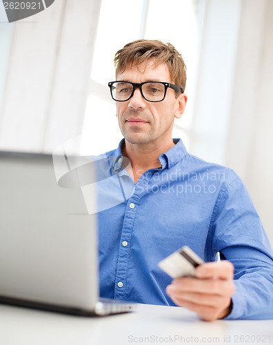 Image of man with laptop and credit card at home