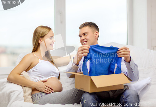Image of happy family expecting child opening parcel box