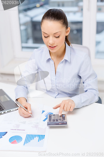 Image of businesswoman with laptop and charts in office