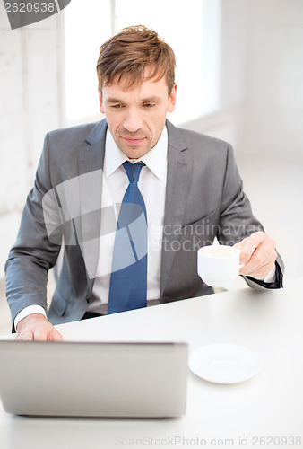 Image of smiling businessman working with laptop computer