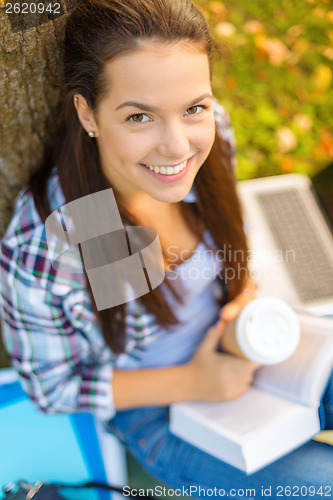 Image of teenager reading book with take away coffee