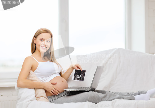 Image of smiling pregnant woman with laptop computer