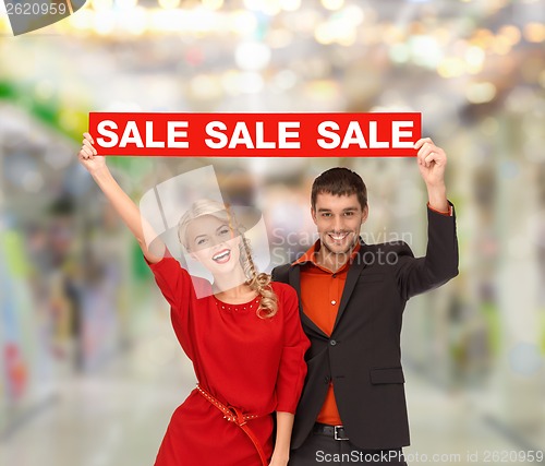 Image of smiling woman and man with red sale sign