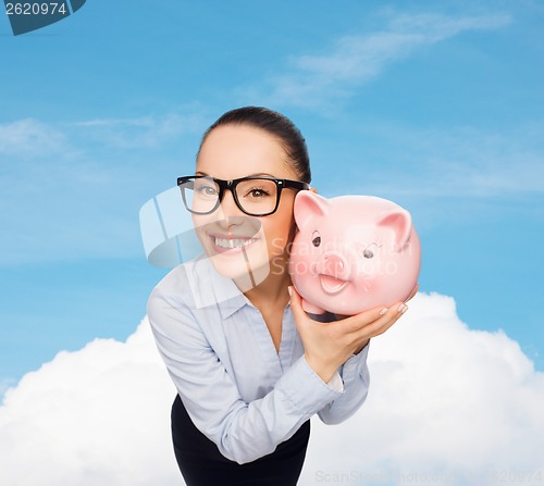 Image of happy businesswoman in eyeglasses with piggy bank