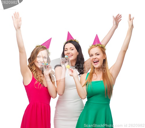 Image of three smiling women in hats blowing favor horns