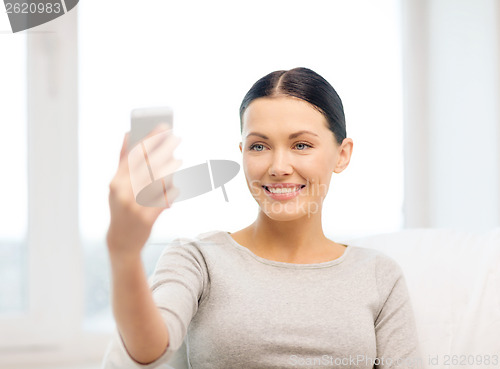 Image of smiling woman with smartphone at home