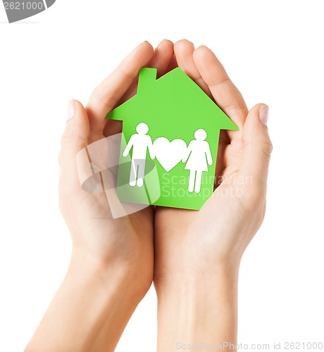 Image of hands holding green house with family