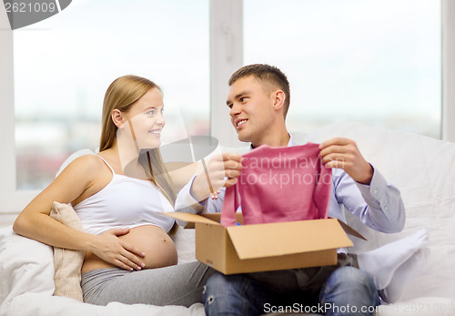 Image of happy family expecting child opening parcel box