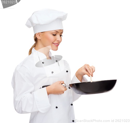 Image of smiling female chef with pan and spoon