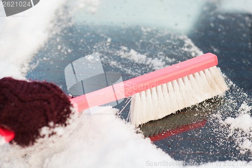 Image of woman cleaning snow from car back window