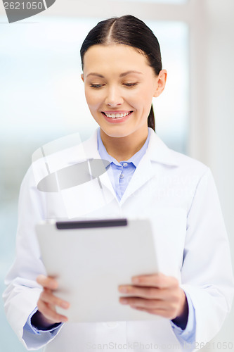 Image of smiling young doctor with tablet pc in cabinet