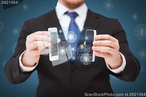 Image of businessman showing smartphones with blank screens