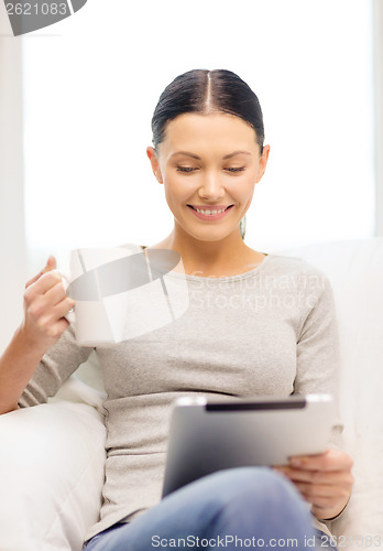 Image of smiling woman with tablet pc computer and cup