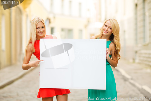 Image of two happy blonde women with blank white board