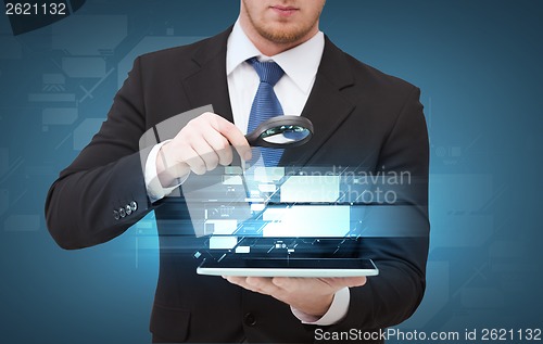 Image of businessman hand holding magnifier over tablet pc