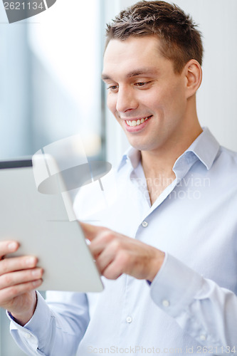 Image of smiling businessman with tablet pc in office