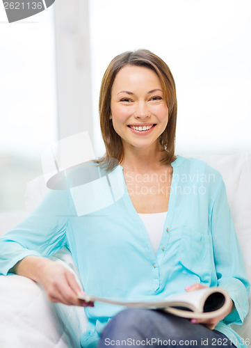 Image of smiling woman reading magazine at home