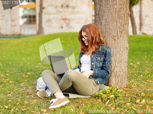 Image of smiling teenager in eyeglasses with laptop