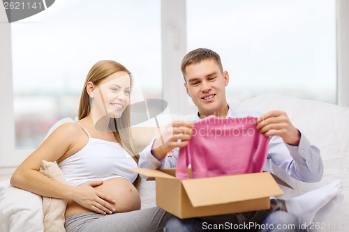Image of happy family expecting child opening parcel box