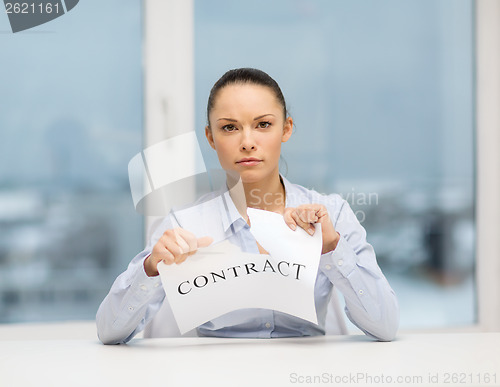 Image of serious businesswoman tearing contract