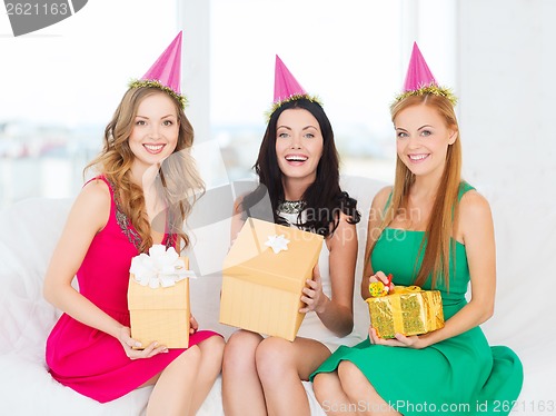 Image of three smiling women in pink hats with gift boxes