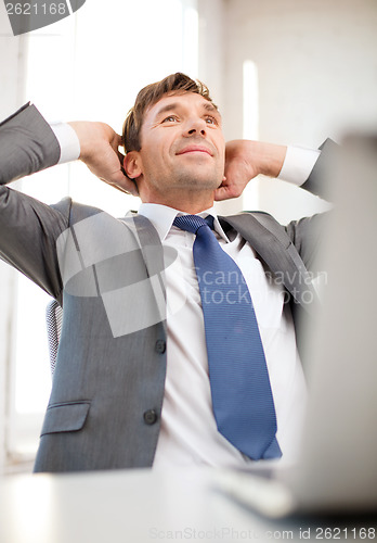 Image of relaxed businessman with laptop in office