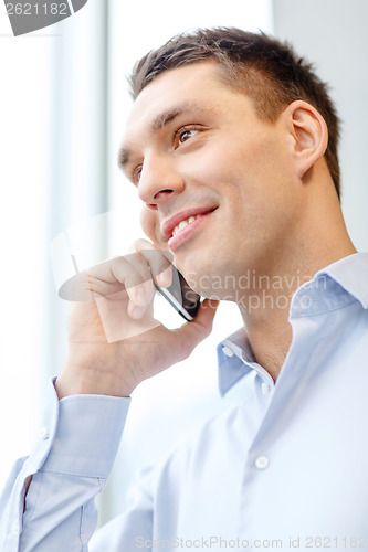 Image of smiling businessman with smartphone in office