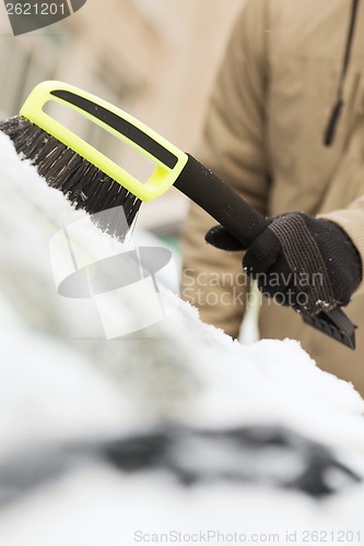 Image of closeup of man cleaning snow from car