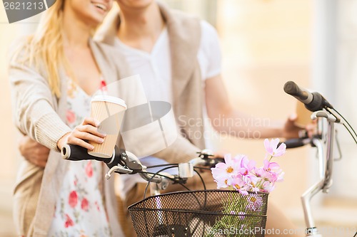 Image of couple holding coffee and riding bicycle