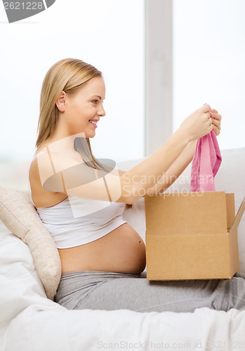 Image of smiling pregnant woman opening parcel box