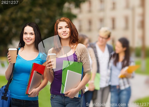 Image of two students with bag, folders, tablet and coffee