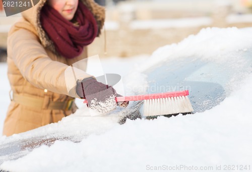 Image of woman cleaning snow from car back window