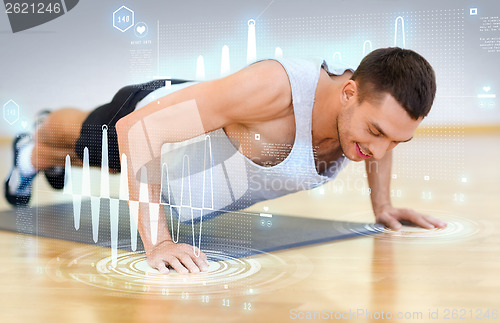 Image of smiling man doing push-ups in the gym