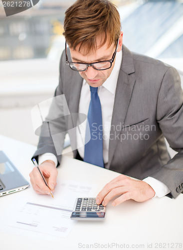 Image of businessman with computer, papers and calculator