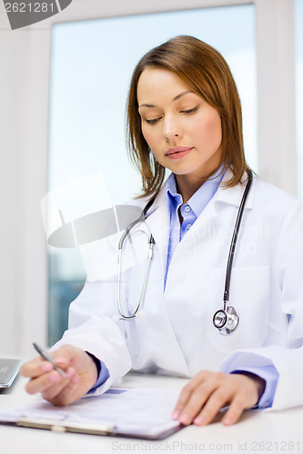 Image of busy doctor with laptop computer and clipboard