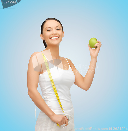 Image of sporty woman with apple and measuring tape