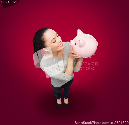 Image of happy woman looking at piggy bank