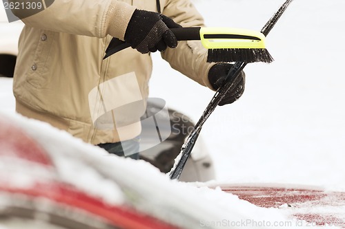 Image of closeup of man cleaning snow from car