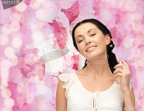 Image of beautiful woman spraying pefrume on her neck