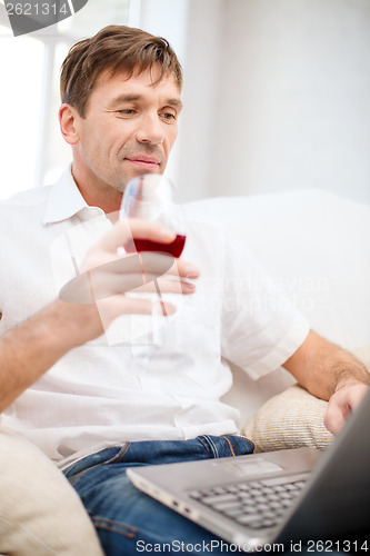 Image of man with laptop computer and glass of red wine