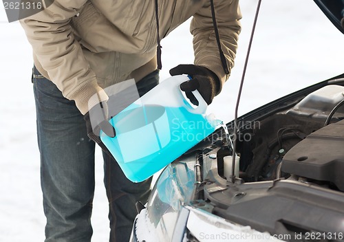 Image of closeup of man pouring antifreeze into water tank