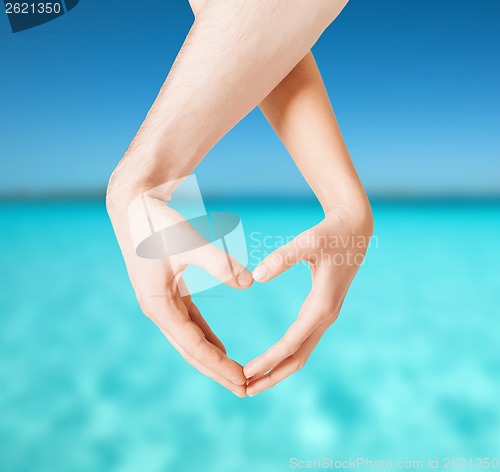 Image of woman and man hands showing heart shape