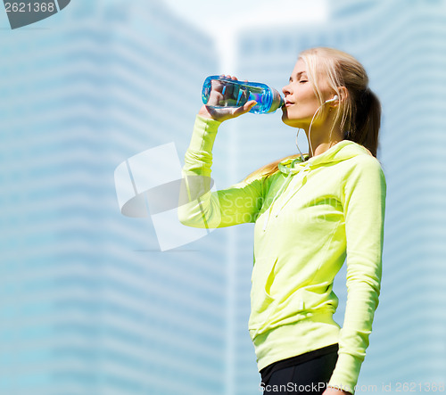 Image of woman drinking water after doing sports outdoors