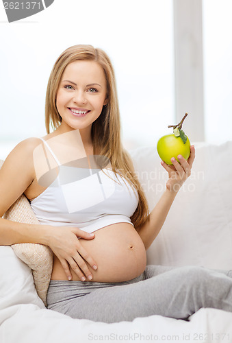 Image of happy pregnant woman with fresh green apple