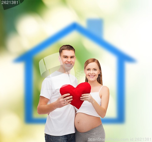 Image of happy young family expecting child with big heart