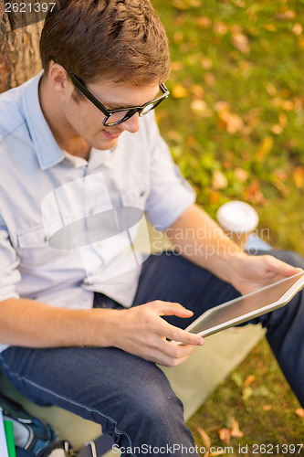 Image of smiling male student in eyeglasses with tablet pc