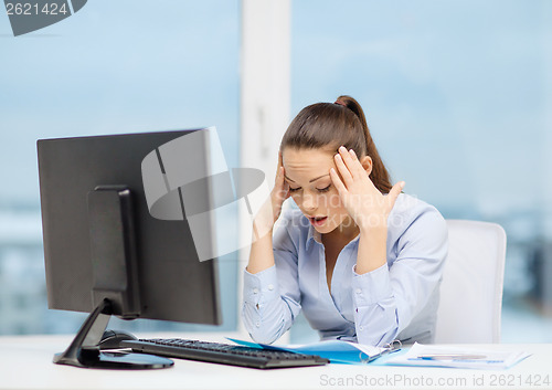 Image of stressed woman with computer and documents