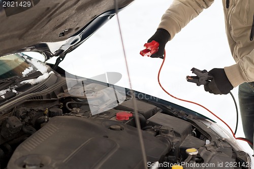 Image of closeup of man under bonnet with starter cables